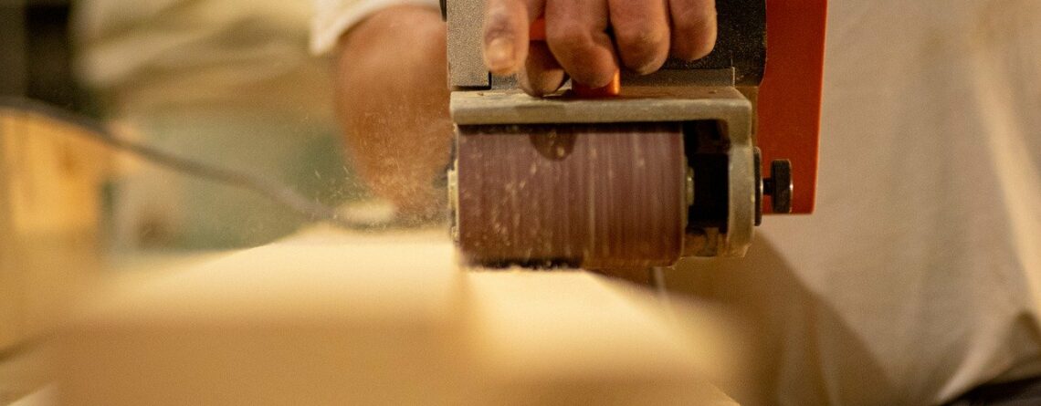 Man using a sanding belt with a push sander