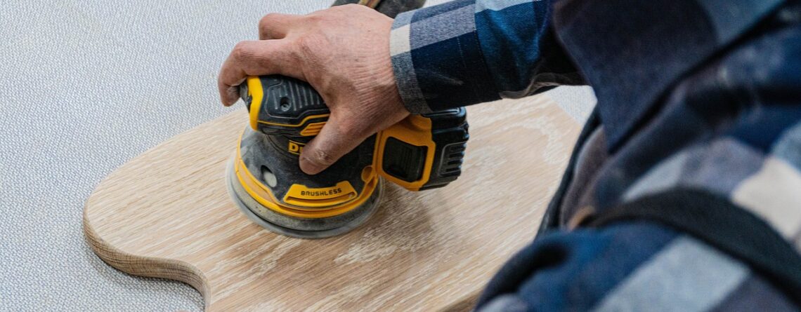 Man sanding a wood piece of worktop with an orbital sander