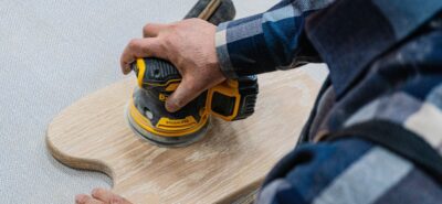 Man sanding a wood piece of worktop with an orbital sander